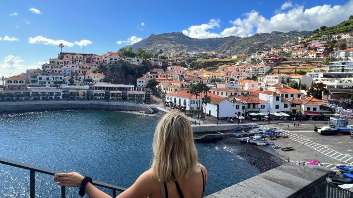 Girl looks at the view of Camara de Lobos, a traditional Madeiran fishing village with a harbour and small beach.