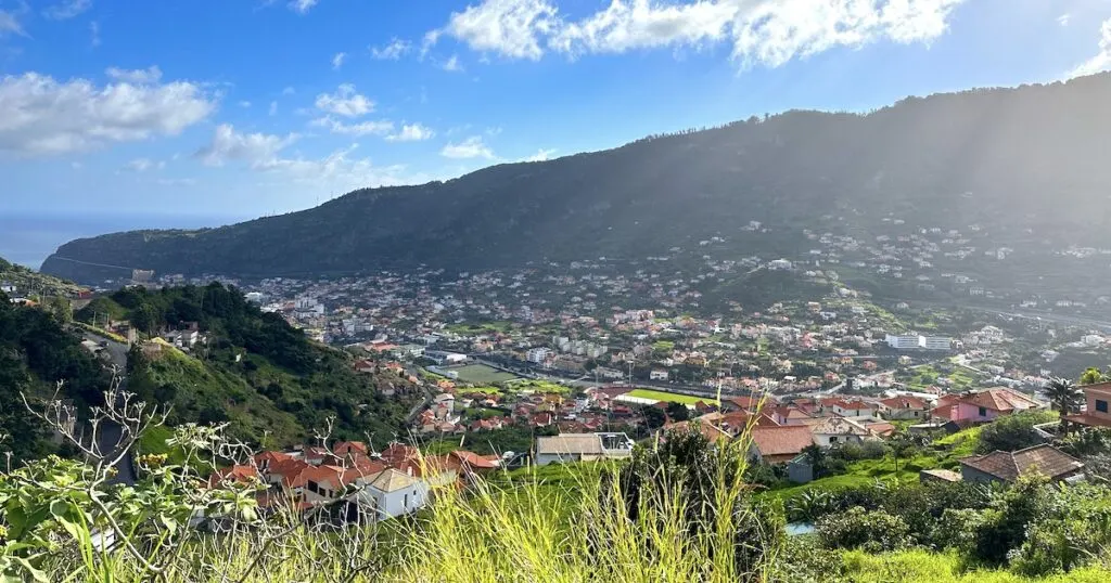 Terracotta tile roofs spread across a green valley in Machico.