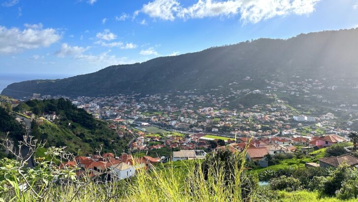 Terracotta tile roofs spread across a green valley in Machico.