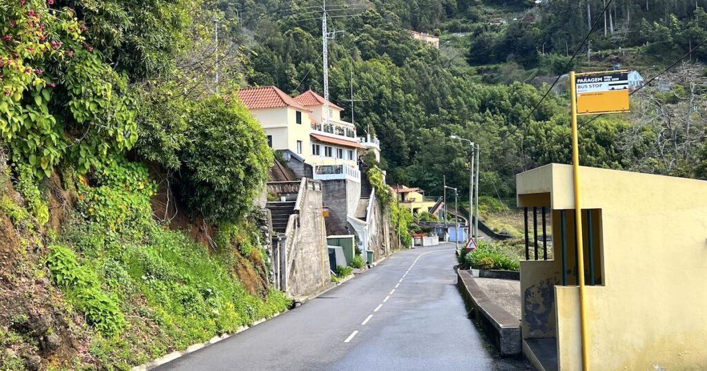 A stone bus shelter on the right hand side of a road in rural Madeira.