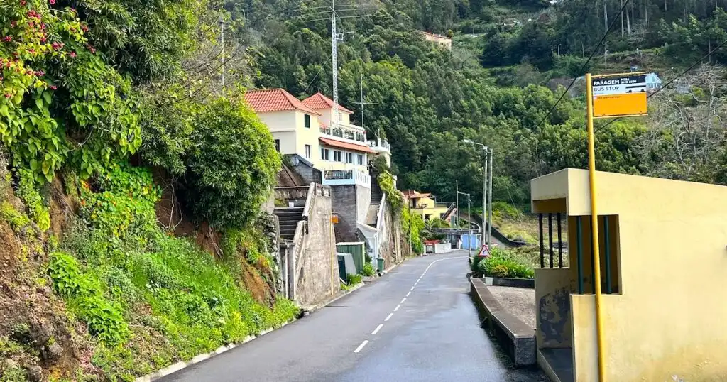A stone bus shelter on the right hand side of a road in rural Madeira.