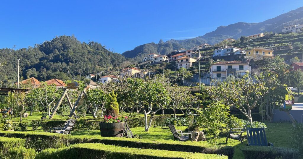 A landscaped garden is backed by a mountain with typical Portuguese houses.