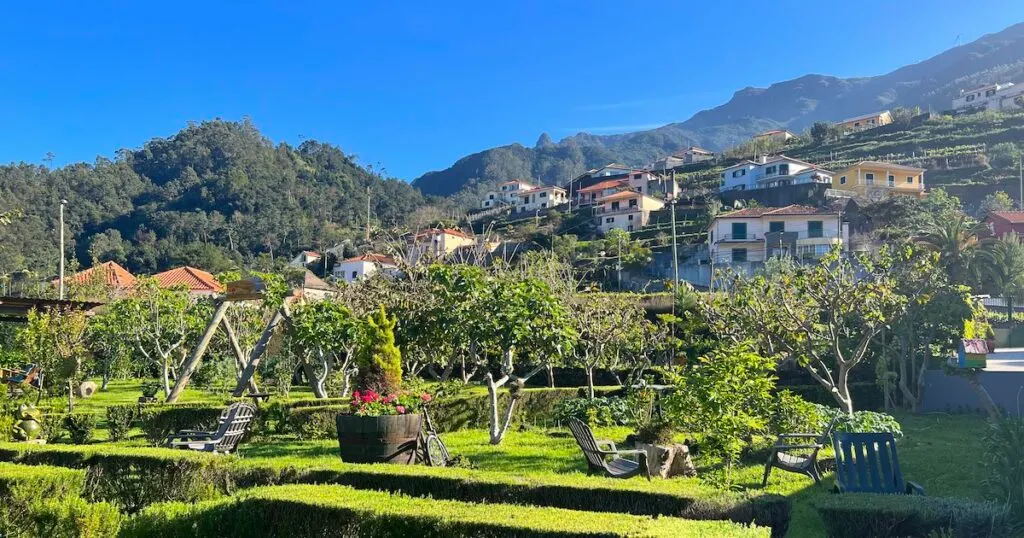 A landscaped garden is backed by a mountain with typical Portuguese houses.