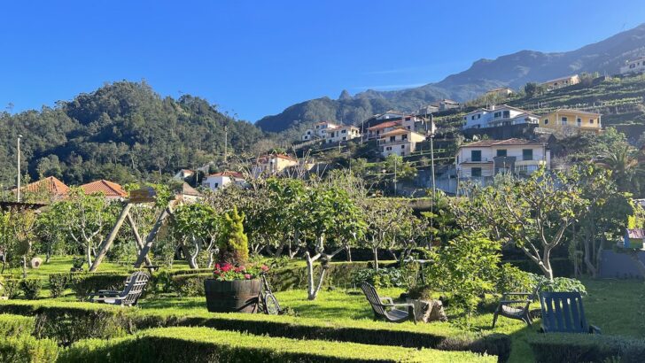 A landscaped garden is backed by a mountain with typical Portuguese houses.