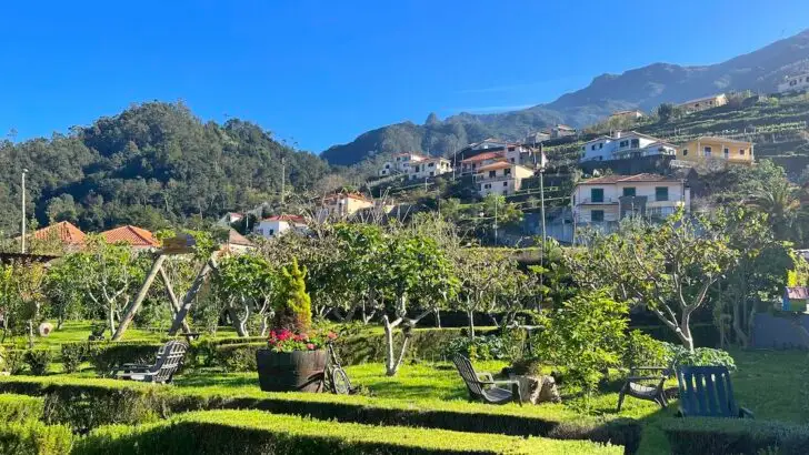 A landscaped garden is backed by a mountain with typical Portuguese houses.