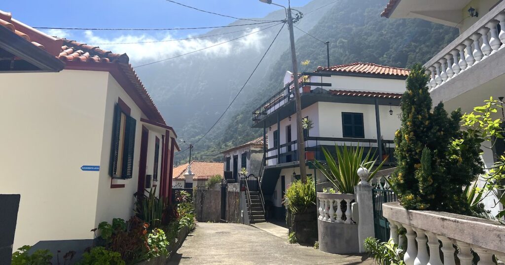 Mist drifts over the mountains behind a street in Seixal.