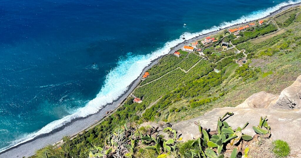 An aerial view over the Atlantic ocean, a pebble beach and vineyards at Fajã dos Padres in Madeira.