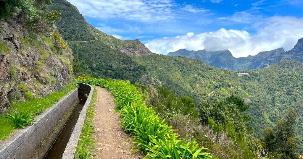 Mountains can be seen in the distance from the Levada das Rabaças hike, a dirt path alongside a levada.