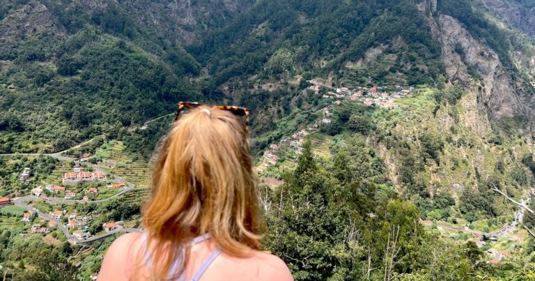 Hiker overlooking the Valley of the Nuns from the Caminho das Voltas trail, with terraced hillsides and mountain villages below.