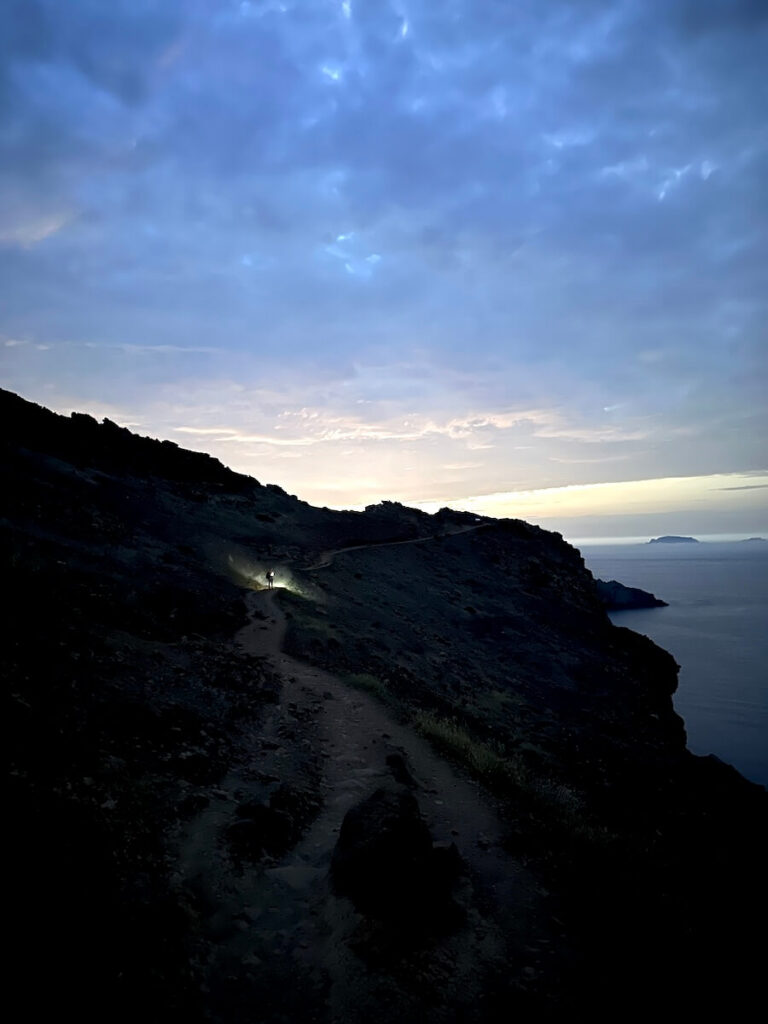 Narrow PR8 footpath crossing a dark coastal hillside beneath the early morning sky.